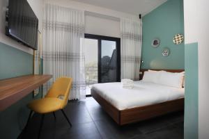 a bedroom with a bed and a chair and a window at Domus Carmel Hotel in Haifa