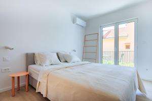 a white bedroom with a bed and a window at Pomalo apartments Vodice in Vodice