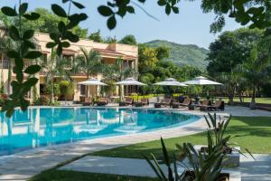 a resort pool with chairs and umbrellas at The Royal Retreat Resort & Spa in Udaipur