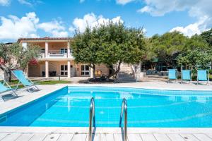 une piscine avec des chaises et une maison en arrière-plan dans l'établissement La Vela Arancione, à Orosei
