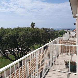 a white railing on a porch with trees and grass at Tonfano Waterfront Penthouse in Marina di Pietrasanta