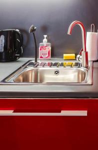 Un fregadero de acero inoxidable en una cocina con un armario rojo. en Central 2BR Flat - free parking - fast Wi-Fi, en Bristol
