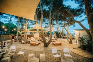 un patio con sillas, mesas y árboles por la noche en Tamarit Beach Resort, en Tamarit