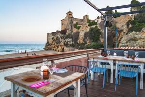 Un restaurante con vista al mar y a un castillo. en Tamarit Beach Resort, en Tamarit