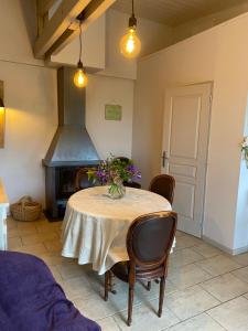 La Maison de Jeanne في Châteney: غرفة طعام مع طاولة ومدفأة +3 صور