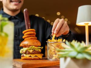 a man sitting at a table with a hamburger and fries at Pullman Sao Paulo Guarulhos Airport in Guarulhos
