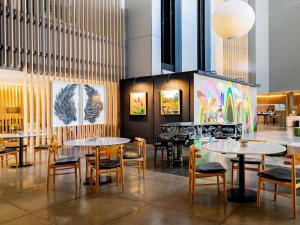 a restaurant with tables and chairs and paintings on the wall at Pullman Sao Paulo Guarulhos Airport in Guarulhos