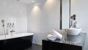 a white bathroom with a tub and a sink at Scandic Malmen in Stockholm