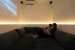two women sitting on a couch in a living room at "サウナ露天風呂貸切" いすみ市一棟貸し古民家ホテル tokoro hotel Isumi in Shiigi