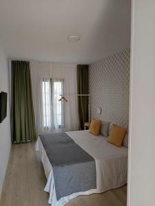 a bedroom with a large bed and green curtains at Casas Verol in Caleta De Fuste