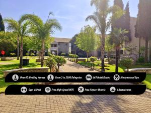 ボクスブルクにあるBirchwood Hotel and OR Tambo Conference Centreのヤシの木が茂る公園前の看板