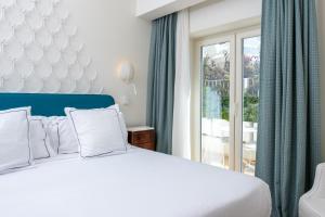 a bedroom with a white bed and a balcony at Pazziella Garden & Suites in Capri