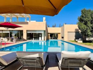 a swimming pool with chairs and a building at Spacious Villa with Mountain Views - 550 m² in Marrakech