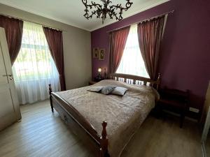 a bedroom with a bed with purple walls and windows at Villa Nelma in Ventspils