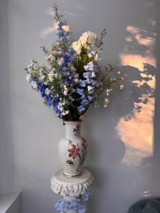 a white vase with blue and white flowers in it at La Cour des Murmures - Logis central d'exception - in Troyes
