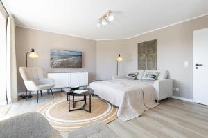 a bedroom with a bed and a desk and a chair at Haus Baltic Flat White in Laboe +35 photos