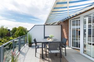 a patio with a black table and chairs on a balcony at Haus Baltic Flat White in Laboe
