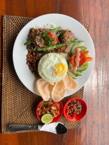 a plate of food with an egg on a table at LAHANGAN SWEET cottages in Culik