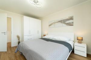 a white bedroom with a bed and a painting on the wall at Beltblick in Marienleuchte