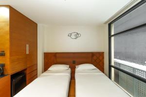 two beds in a small room with a window at Marvin Suites Hotel in Bangkok