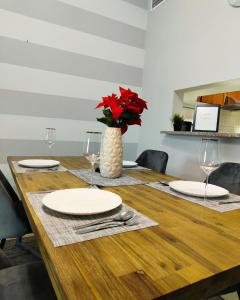 un tavolo di legno con piatti e un vaso con fiori rossi di Charming & Comfortable 1BR Jumeirah Bay X1 JLT a Dubai
