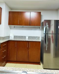 una cucina con mobili in legno e un frigorifero in acciaio inossidabile di Charming & Comfortable 1BR Jumeirah Bay X1 JLT a Dubai Altre 7 foto
