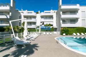 a resort with a swimming pool and chairs and a building at Residence Maricel in Lido di Jesolo