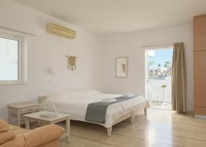 um quarto branco com uma cama e um sofá em Reina Apartments em Georgioupolis