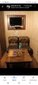 a room with a couch and a table with a bottle on it at Hotel Sita Inn in Shimla