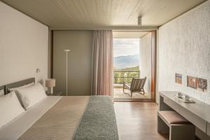 a bedroom with a bed and a balcony with a chair at Amalia Hotel Delphi in Delfoi