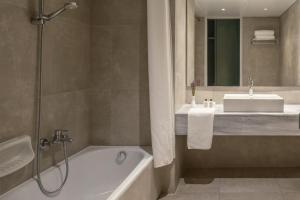 a bathroom with a tub and a sink and a bath tub at Amalia Hotel Delphi in Delfoi