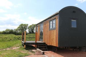 a tiny house sitting on display in a field at Oak Moor Shepherd Hut - Brecon Beacons, LD3 7TD in Tal-y-llyn