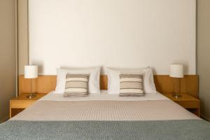 a bedroom with a bed with pillows and two lamps at Amalia Hotel Delphi in Delfoi
