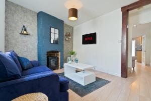 ein Wohnzimmer mit einem blauen Sofa und einem Tisch in der Unterkunft Spacious Cosy City Centre House - Perfect for Contractors & Work in Gillingham