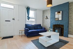 ein Wohnzimmer mit einer blauen Couch und einem Kamin in der Unterkunft Spacious Cosy City Centre House - Perfect for Contractors & Work in Gillingham