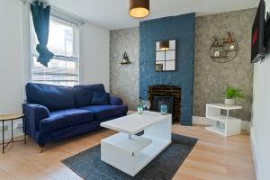 ein Wohnzimmer mit einer blauen Couch und einem Kamin in der Unterkunft Spacious Cosy City Centre House - Perfect for Contractors & Work in Gillingham + 25 Fotos