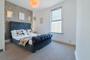 ein Schlafzimmer mit einem Bett und einer blauen Ledercouch in der Unterkunft Spacious Cosy City Centre House - Perfect for Contractors & Work in Gillingham