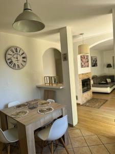 a dining room table with white chairs and a clock on the wall at Maison au calme, nature et paix in Trélissac +6 photos