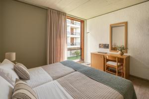 a bedroom with a bed and a desk and a window at Amalia Hotel Delphi in Delfoi