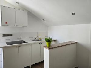 Una cocina blanca con gabinetes blancos y un fregadero. en Villa Mandza, en Novalja