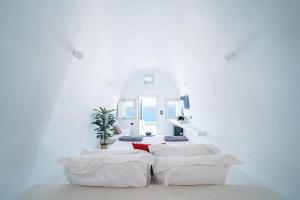 a white room with two white beds in it at Santonero in Akrotiri