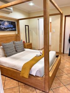 a bed with a wooden frame in a room at Bothabelo Luxury Villas in Phalaborwa