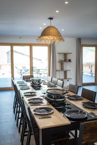 a long table with chairs and a large room with windows at Renovated apartment with terrace for 14 people in Saint-Jean-de-Maurienne