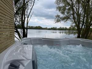 a tub with water in it next to a lake at 1 Willowmere lakeside Hideaway in Baston