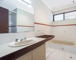 une salle de bain avec un lavabo, une baignoire et un miroir dans l'établissement 20 OFF Affortable Long Stay 4 Queen Bed House Near Uni City Swan River, à Perth