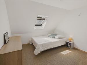a white bedroom with a bed and a window at Maison pour 6 avec jardin à 1 km de la plage in Penmarcʼh