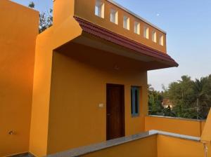 a yellow house with a balcony with a door at Villa De Auroville Couple Friendly Property in Kottakupam