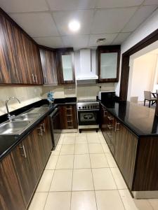 ドバイにあるBeachside 2BR Marina Viewsのキッチン(木製キャビネット、黒いカウンタートップ付)