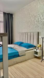 Un dormitorio con una cama grande con sábanas azules. en уютная и стильная студия в новом ЖК Панорама Парк, en Kostanái 27 fotos más