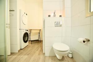 a white bathroom with a toilet and a washing machine at אירופה בוטיק כנרת - דירת 4 חדרי שינה עם נוף לכנרת in Tiberias +53 photos